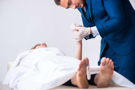 Police coroner examining dead body corpse in morgue
