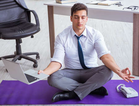 Man meditating in the office to cope with stressの写真素材