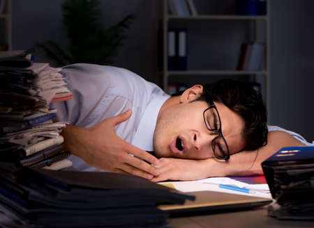 Young businessman working overtime late in officeの写真素材