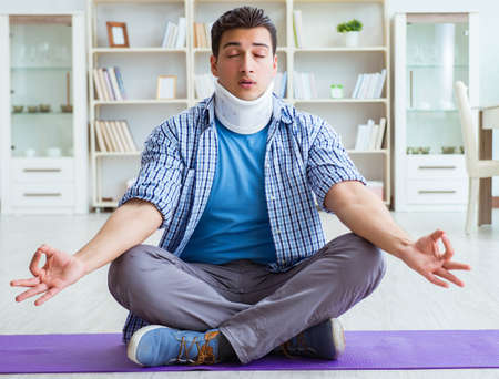 Man with neck injury meditating at home on floorの写真素材