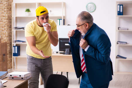 Young male courier delivering pizza to the officeの写真素材