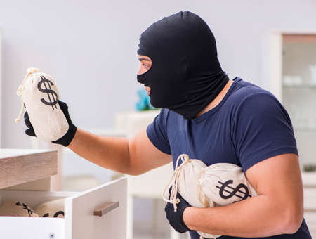 Robber wearing balaclava stealing valuable things