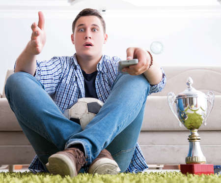Young man student watching football at home