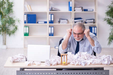 Old businessman rejecting new ideas with lots of papersの写真素材