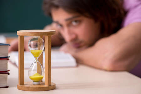 Young male student in the classroom at time management concept