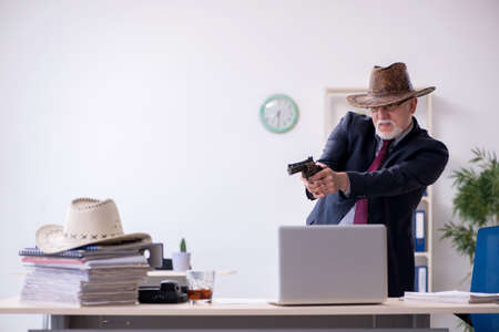 Funny old boss in cowboy hat in the officeの写真素材