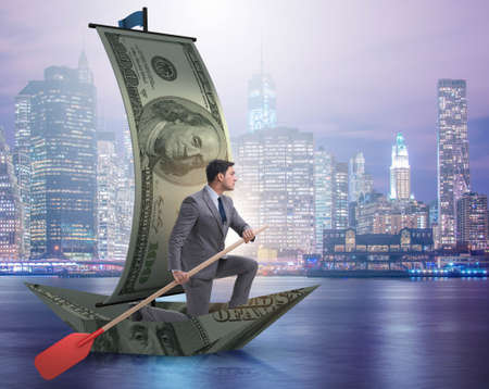 Businessman rowing on dollar boat in business financial conceptの写真素材