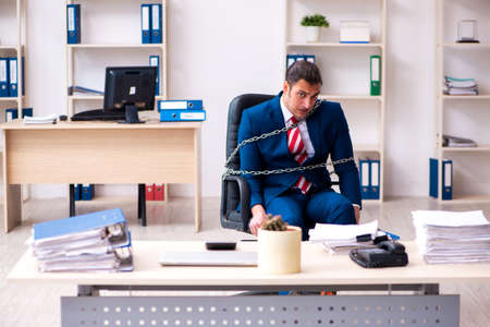 Chained male employee working in the officeの写真素材