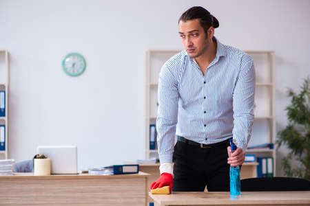 Young male employee cleaning office during pandemicの写真素材