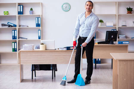 Young male employee cleaning office during pandemicの写真素材