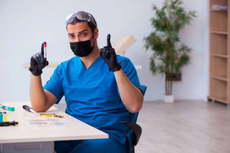 Young male biochemist testing blood samples in pandemic conceptの写真素材