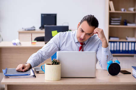 Young male employee in time management conceptの写真素材