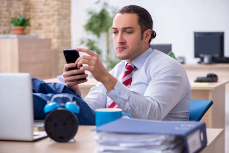 Young male employee in time management conceptの写真素材