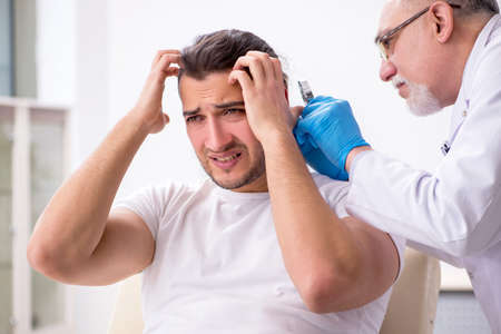 Young man visiting experienced doctor dermatologistの写真素材