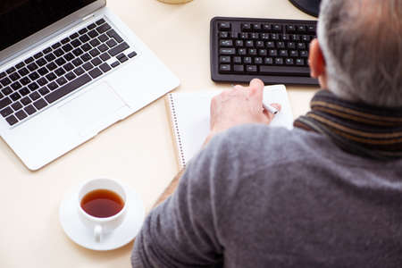Old male employee working from house during pandemic