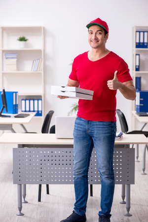 Young male courier delivering pizza to the officeの写真素材