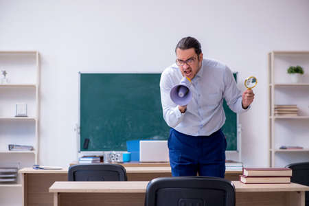 Young male teacher in front of green boardの写真素材