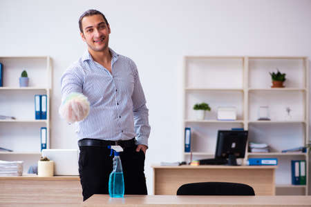 Young male employee cleaning office during pandemicの写真素材