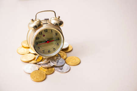 Small alarm-clock and bitcoins on the tableの写真素材