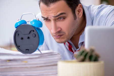 Young male employee in time management conceptの写真素材