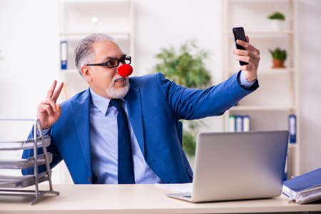Old businessman clown working in the officeの写真素材