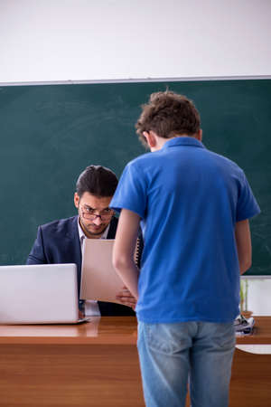 Young male teacher and schoolboy in the classroomの写真素材