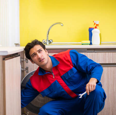 Repairman repairing washing machine in the kitchenの写真素材