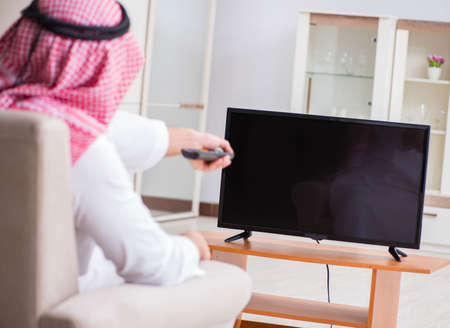 Arab businessman watching tv at homeの写真素材