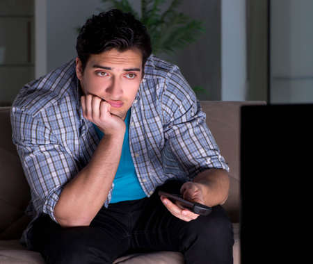 Young man watching tv late at nightの写真素材
