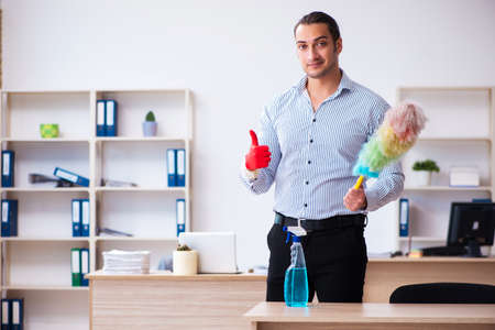 Young male employee cleaning office during pandemicの写真素材