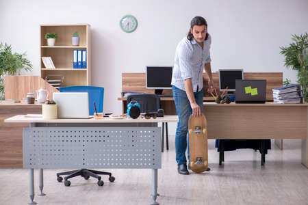Young male employee with skateboard in the officeの写真素材