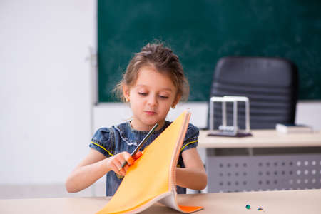 Small girl and thumbtacks in the classroomの写真素材