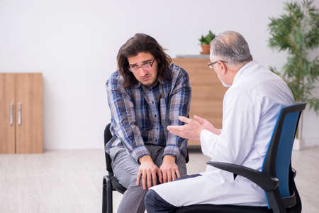 Young male patient visiting experienced doctor psychiatristの写真素材