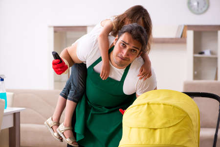 Young male contractor cleaning the house with his small daughterの写真素材
