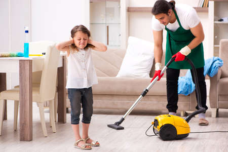 Young male contractor cleaning the house with his small daughterの写真素材