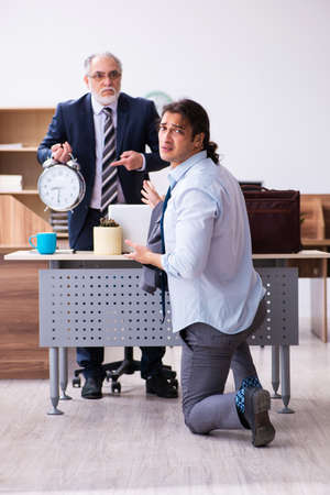Old boss and his male secretary employee in time management concの写真素材