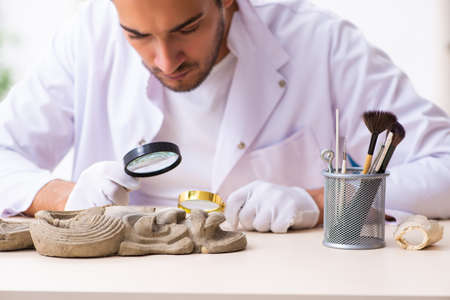 Young male archaeologist studying ancient african stonemaskの写真素材