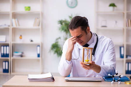Young male doctor in time management concept