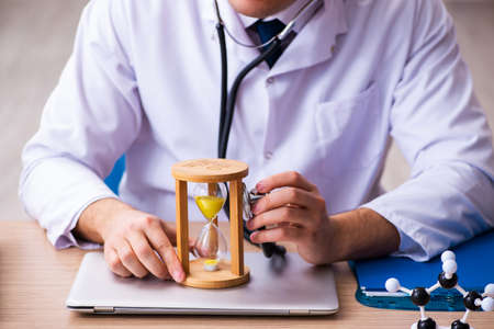 Young male doctor in time management conceptの写真素材