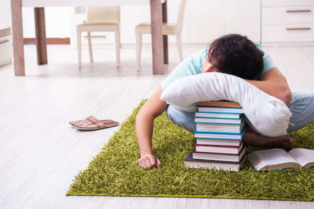 Young male student being tired preparing for exams at homeの写真素材