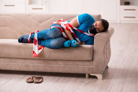 Young man watching tv at home in pandemic concept