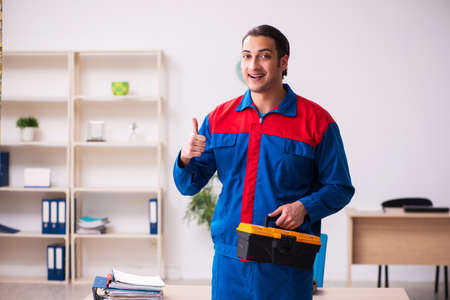 Young male contractor repairing furniture in the officeの写真素材