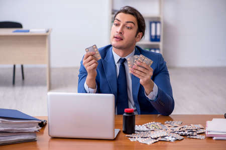 Young male sick employee suffering at workplaceの写真素材