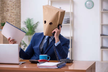 Young male employee with box instead of his headの写真素材