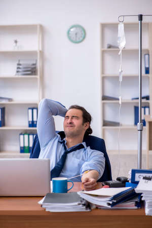 Young male employee suffering at workplaceの写真素材