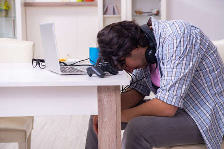 Young male student playing computer games at homeの写真素材