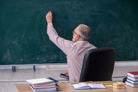 Old male teacher sitting in the classroomの写真素材