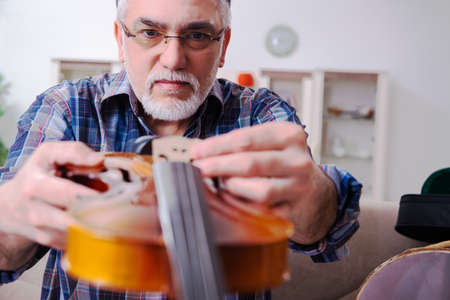 Senior male repairman repairing musical instruments at homeの写真素材