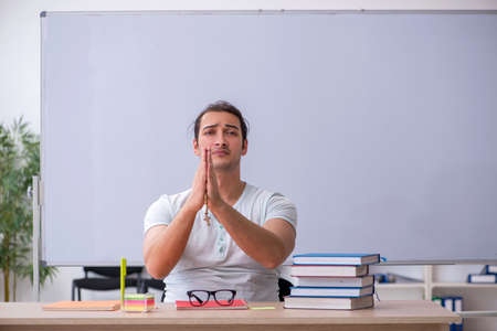 Young male teacher student sitting in the classroomの写真素材