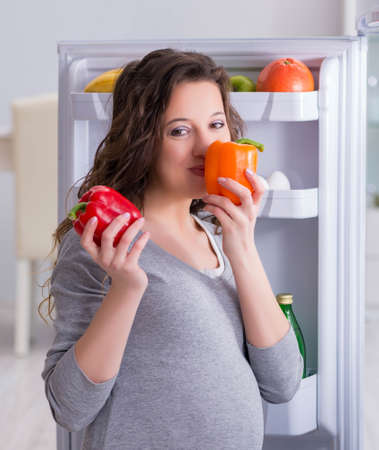 Pregnant woman near fridge looking for food and snacksの写真素材